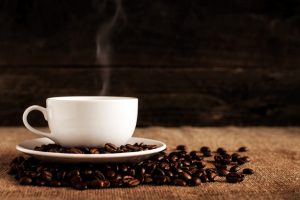 Smoking cup of coffee with coffee seeds